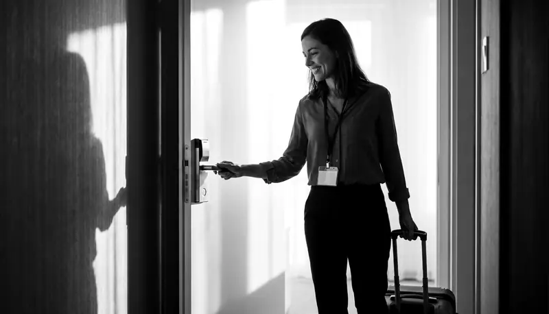 Ilustración: una congresista con maleta sonríe al abrir la puerta de su habitación de hotel.